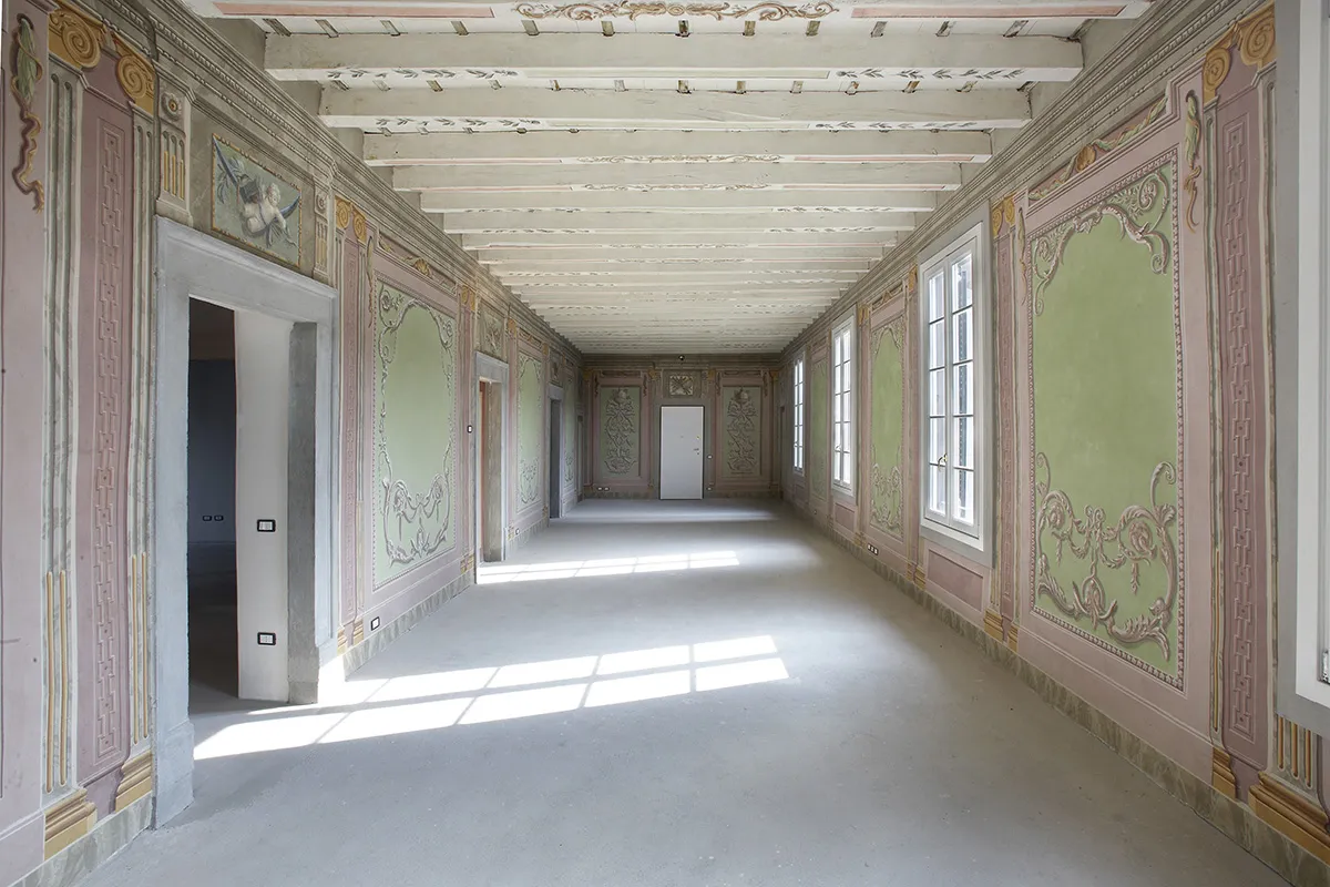 Salone con pareti affrescate rosa antico e verde salvia e soffitto a travi dipinte