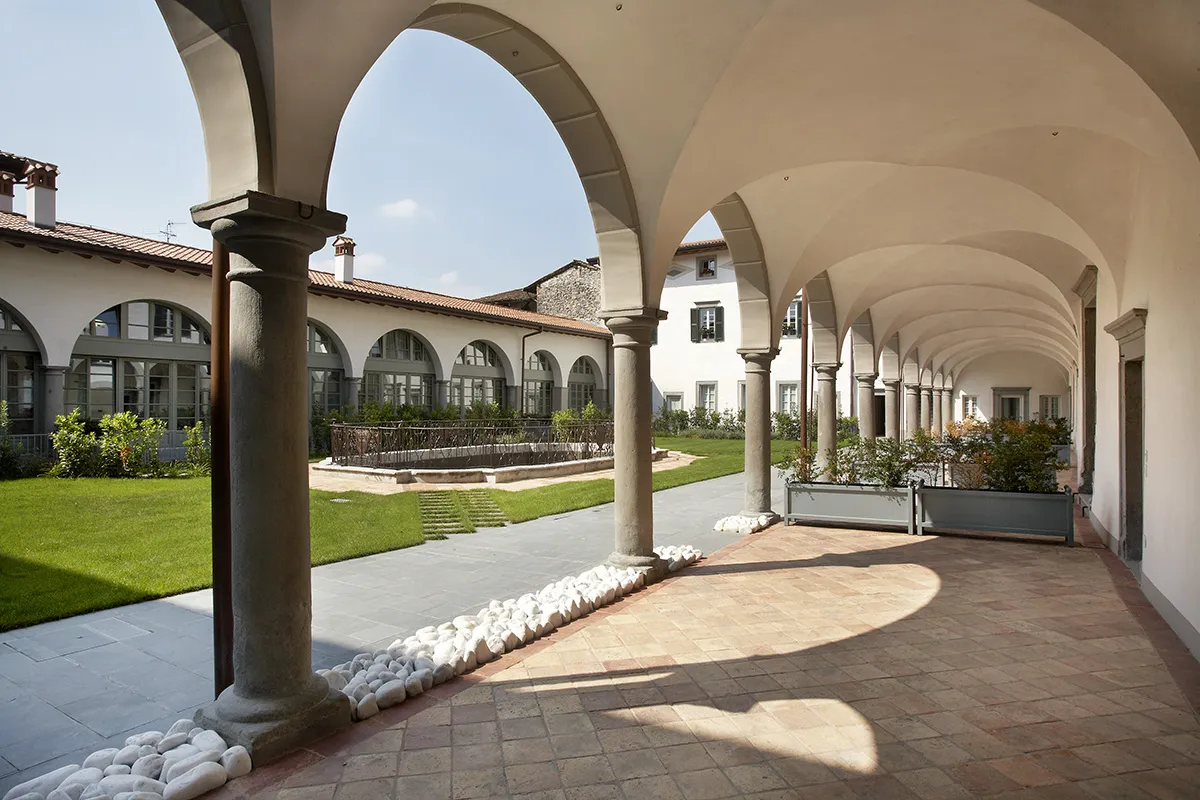 Il porticato con colonne in pietra e volte a crociera, aperto sulla corte e sul prato